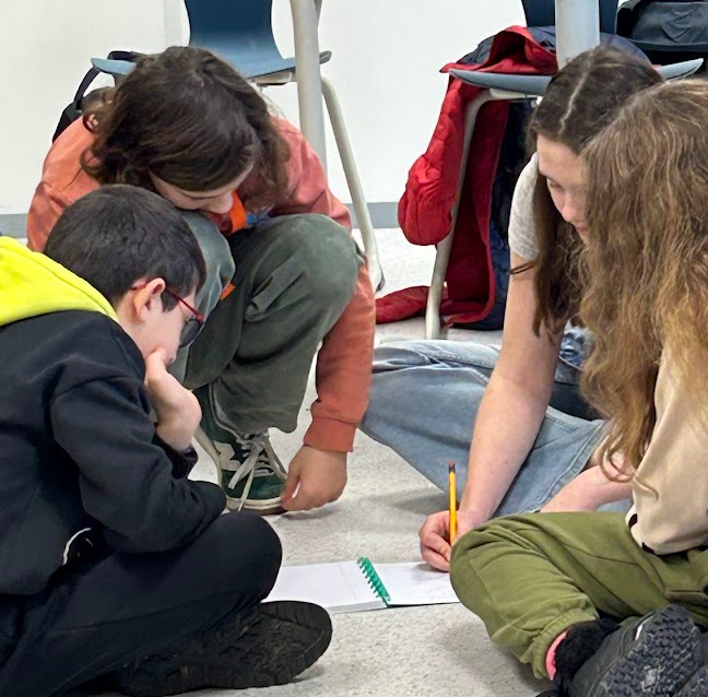 Three students solving a problem together on the classroom floor